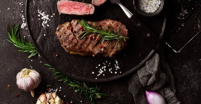photo-grilled-ribeye-beef-steak-steak-fork-black-plate-top-view-black-stone-background-wide-2
