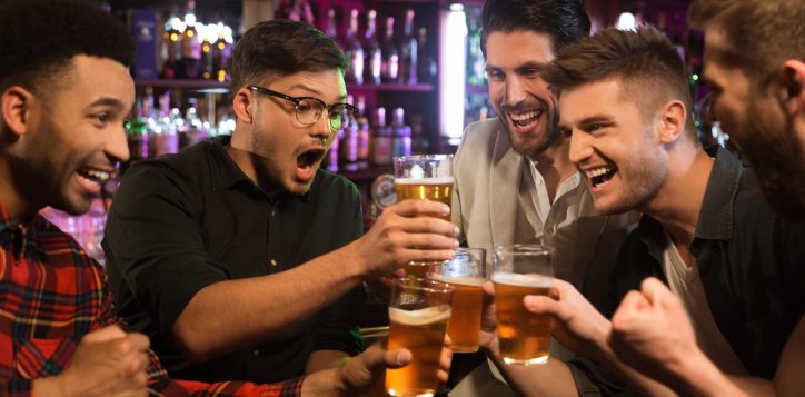 happy-male-friends-clinking-with-beer-mugs-pub