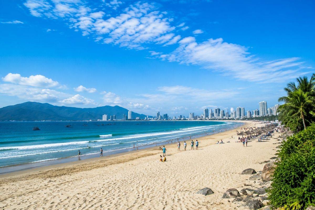 Wide white sand at Thanh Binh Beach with mountains and the city in the distance