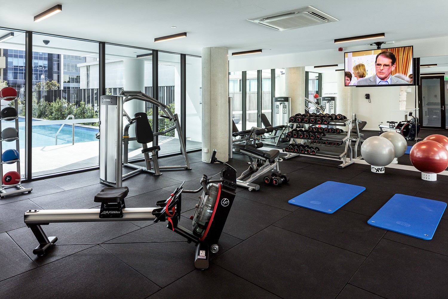Gym with fitness machines and weights looking out over pool area