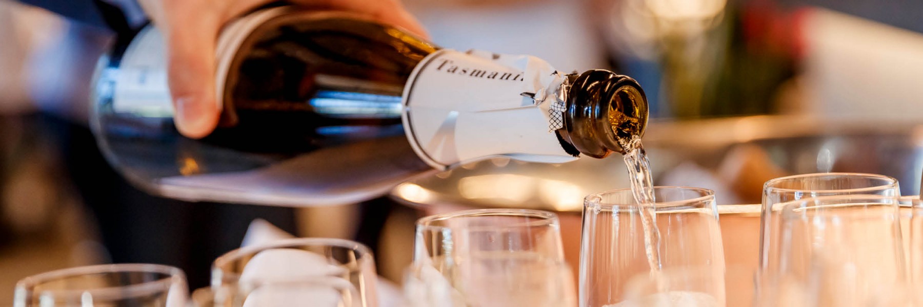 Pouring a glass of sparkling wine from a bottle with the word Tasmania on the neck