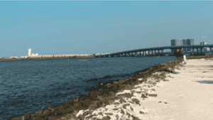 Scenic view from the Coastal Serenity Tour in Pantai Indah Kapuk, showing a coastal path and bridge under clear skies.