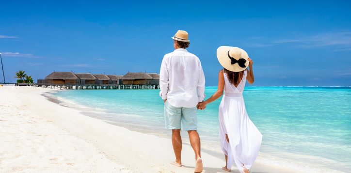 happycoupleinwhiteclothingandwithhatswalksdown