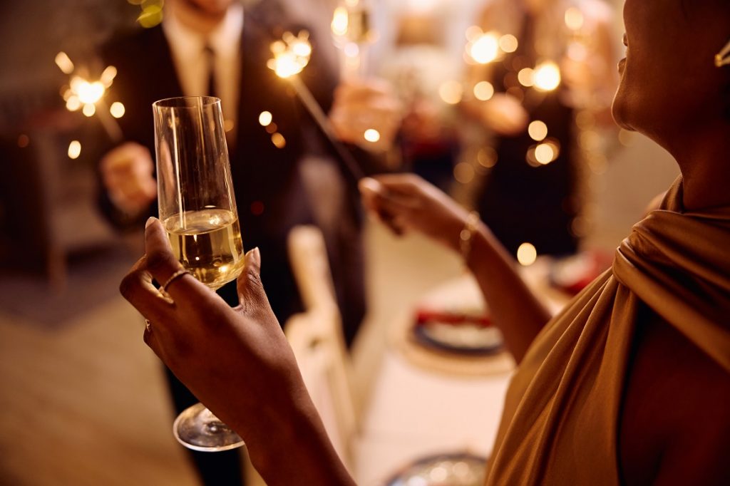 Close up of African American woman drinking champagne while celebrating New Year with her friends.