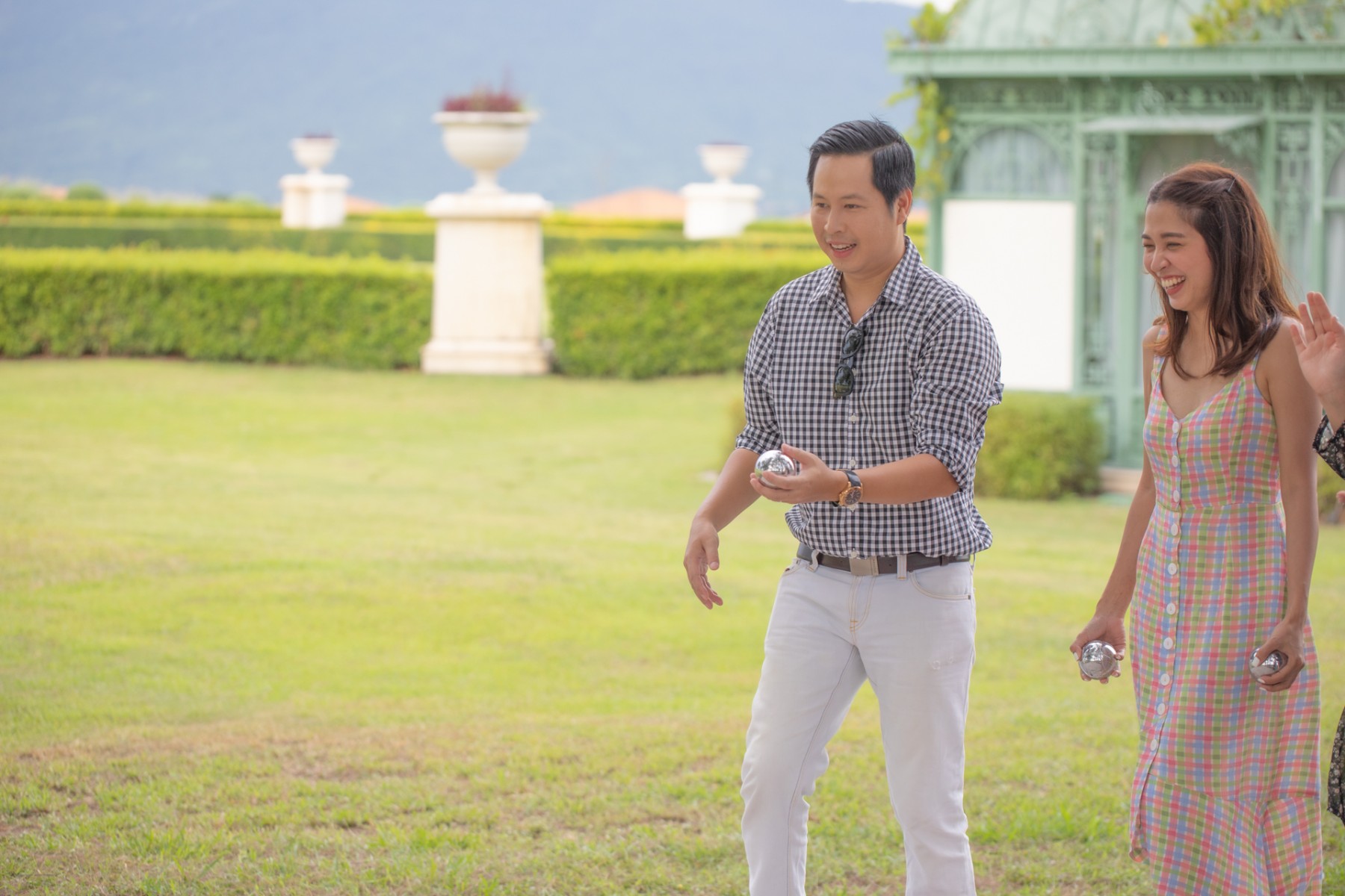 Couple playing petanque on the garden lawn at Mövenpick Resort Khao Yai