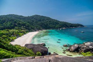 A breathtaking tropical beach view of the Similan Islands with turquoise waters and lush green hills in the Andaman Sea, Khao Lak, Thailand.