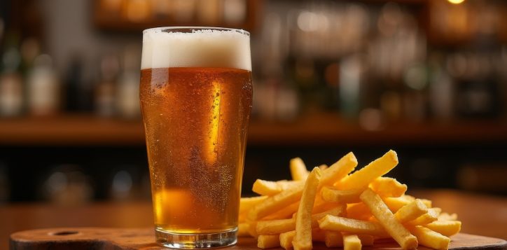 pint-of-golden-beer-with-frothy-foam-served-alongside-crispy-french-fries-on-a-wooden-board-in-a-cozy-bar-setting-with-warm-lighting