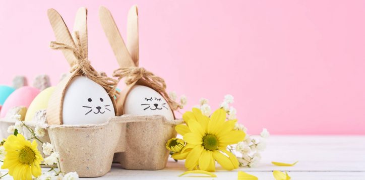 easter-colored-eggs-with-painted-faces-paper-tray-with-decorationd-pink-background