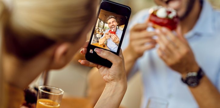 closeup-woman-taking-picture-her-boyfriend-who-is-eating-donut-cafe_resized