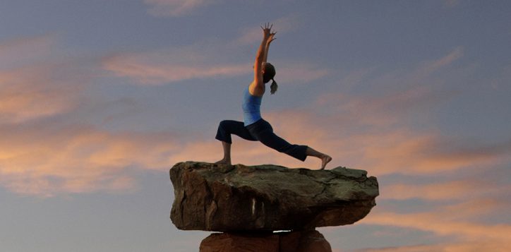 caucasian-woman-practicing-yoga-on-top-of-rock-formation