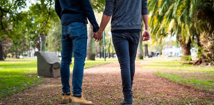 portrait-without-head-of-young-gay-couple-holding-hands-and-walking-in-the-park