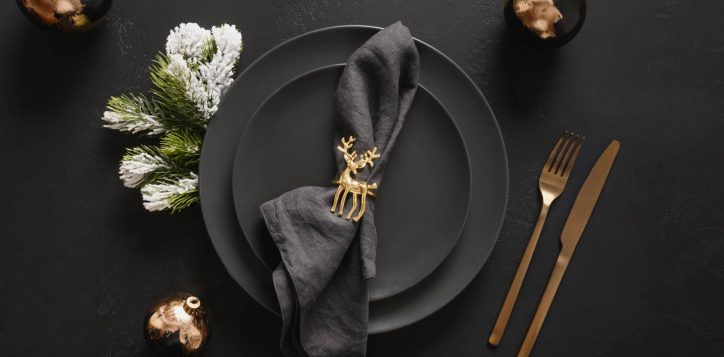 christmas-table-setting-with-black-plate-golden-decorations-black-background