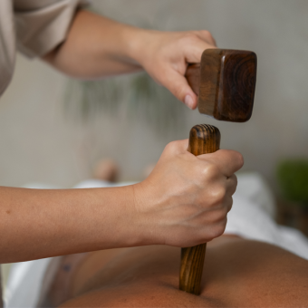 Therapist performing Tok Sen massage using traditional wooden tools at A VIDA Spa, Mövenpick Myth Hotel Patong Phuket
