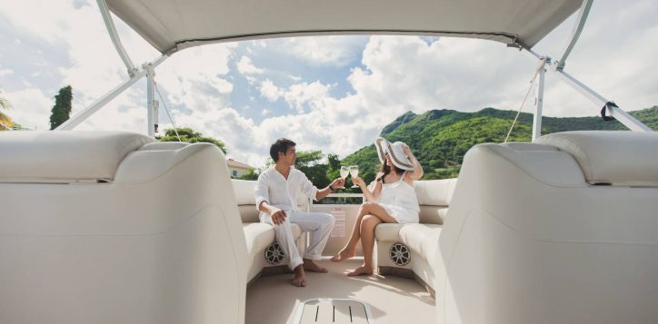 smiling-young-couple-holding-glasses-with-champagne-looking-each-other-while-sitting-board-yacht
