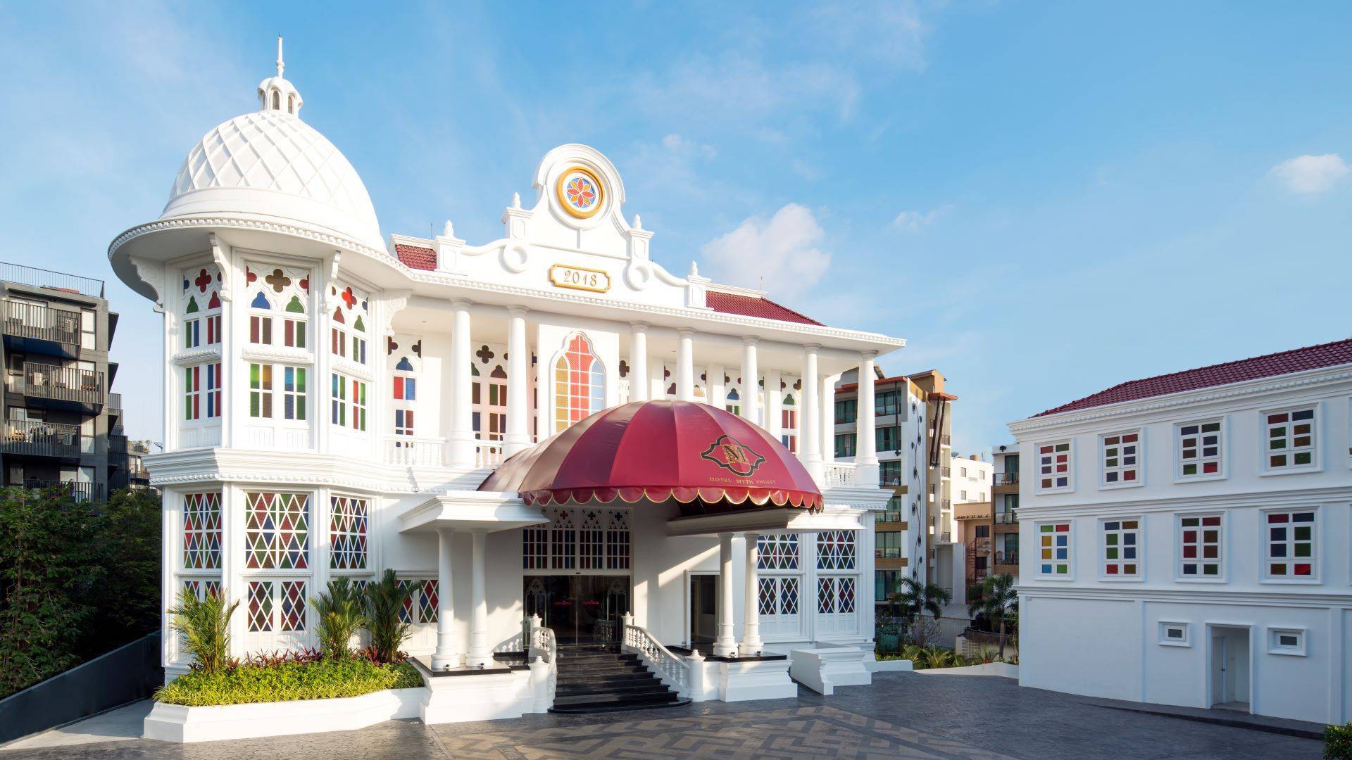 Elegant white hotel building with red dome entrance and colorful stained-glass windows.