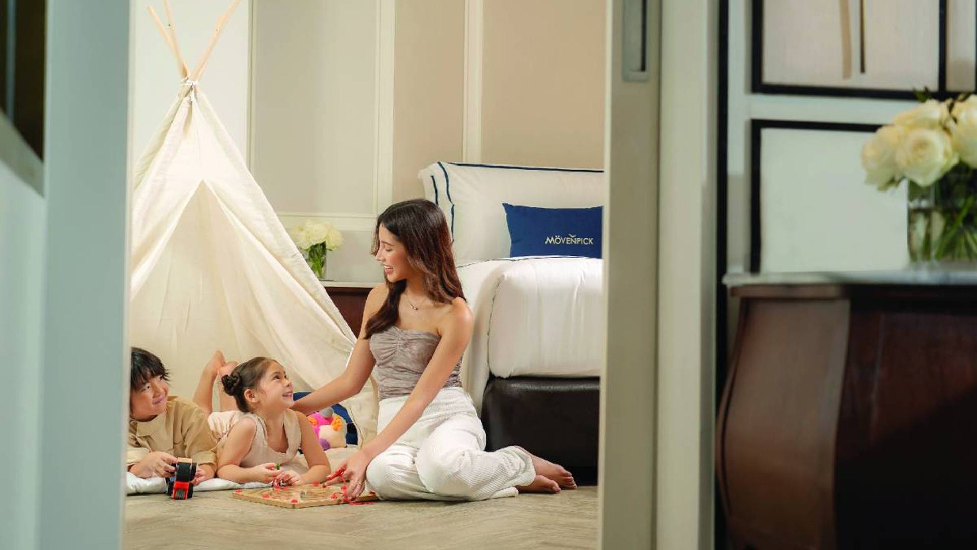 Mother playing with children in a family-friendly hotel room at Mövenpick.