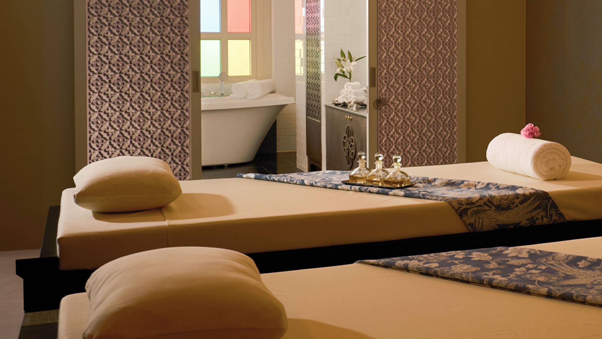 Luxury spa room with massage beds, oils, and bathtub.