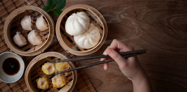 overhead-shot-woman-eating-chinese-steamed-dumpling-steamed-pork-bun-bamboo-steamer
