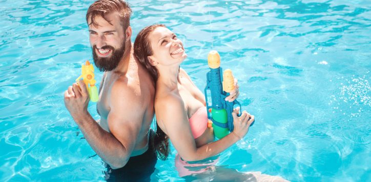 funny-couple-stands-swimming-pool-they-pose-smile-girl-looks-up-they-hold-water-guns-hands-they-are-ready-shoot-1