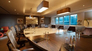Modern executive boardroom with large wooden conference table, ergonomic leather chairs, and bright natural lighting at Pullman Dubai JLT