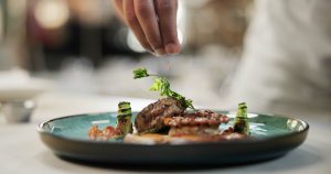 Chef finishing gourmet dish at Pullman Dubai Jumeirah Lakes Towers restaurant in JLT Dubai