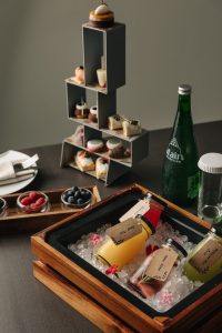 Gourmet afternoon tea selection and luxury dessert welcome amenities served on a modern tiered display stand at Pullman Dubai Jumeirah Lakes Towers.