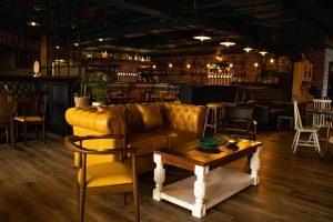 Cozy interior lounge seating with a yellow chesterfield leather sofa and wooden tables inside The Black Sheep British Gastropub in JLT.
