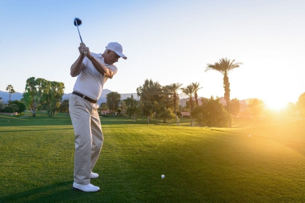 golfer swinging on a sunny course with bright light over the grass