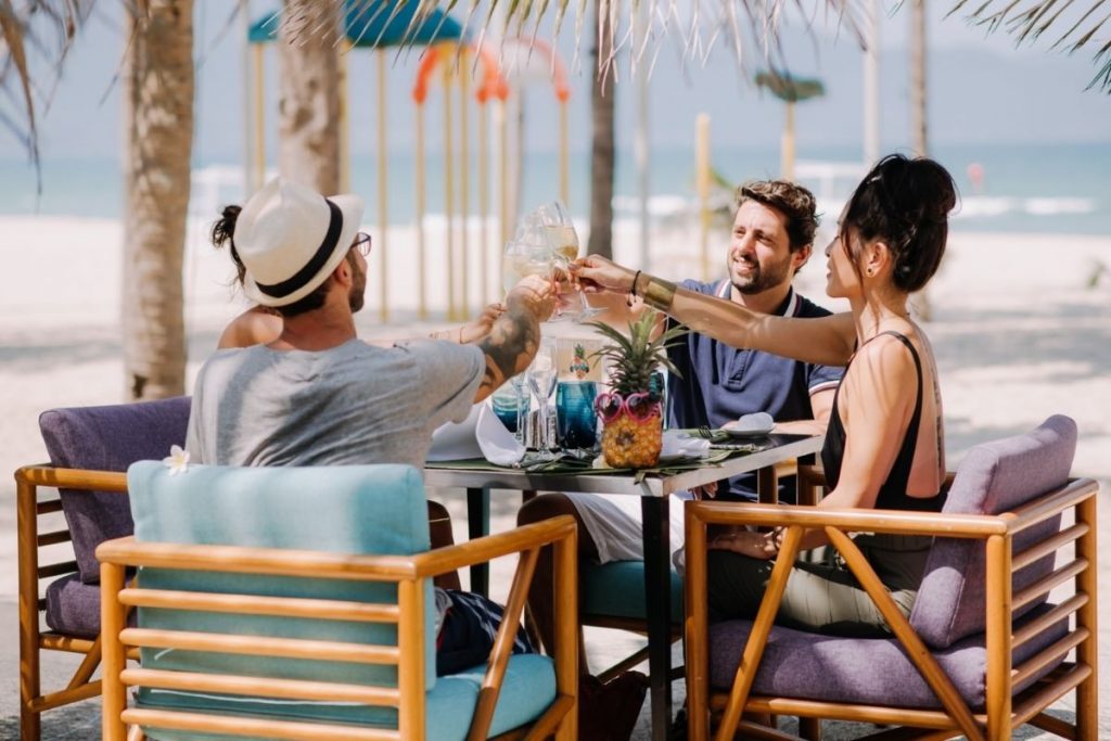 friends enjoying drinks together at an outdoor beachside table.