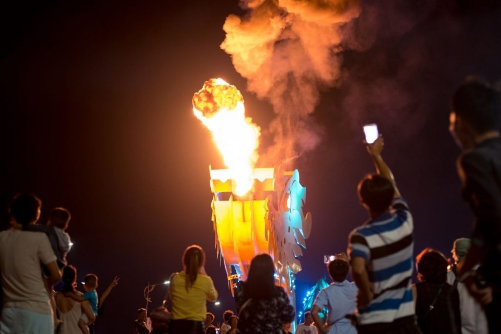 Crowd watching a dragon bridge's fire show at night