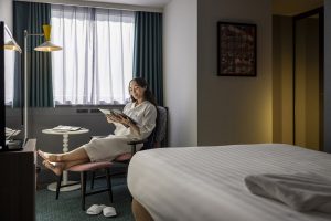female with bathrobe on the chair reading magazine in standard semi double room